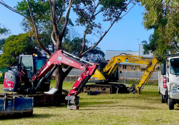 Excavators on green grass after being serviced in Ocean Grove by Sartori's diesel mechanics